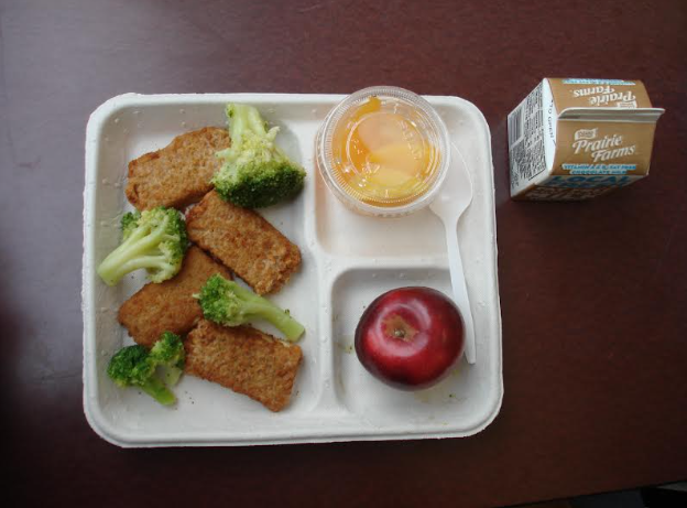 Pizza crunchers with a side of broccoli, a fruit cup, apples, and chocolate milk as a drink