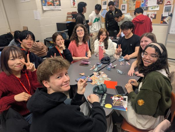 Sophomore Otto Grant, freshmen Helix Swindler and Ava Rush and senior Cristian Hurtado sit with the Japanese students to make origami
